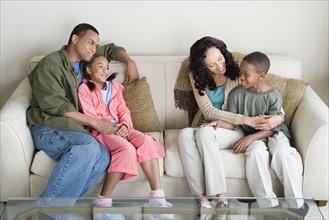 Parents with children (10-13) relaxing on sofa. Photo : Rob Lewine