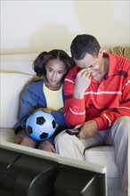 Father and Daughter (10-11) watching sports on tv. Photo : Rob Lewine