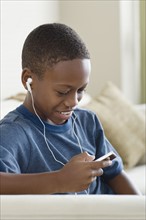 Boy (12-13) listening to music on mp3 player. Photo : Rob Lewine