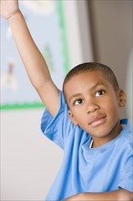 Schoolboy (6-7) raising hand. Photo : Rob Lewine