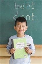 Smiling boy (6-7) showing notebook in classroom. Photo: Rob Lewine