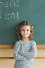 Girl (6-7) in classroom against blackboard. Photo : Rob Lewine