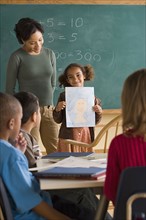 Girl (6-7) showing her drawing in classroom. Photo : Rob Lewine