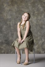 Portrait of smiling girl (8-9) sitting on stool. Photo : Rob Lewine