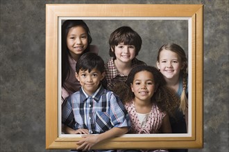 Children (6-7, 8-9) posing together in frame, studio shot. Photo : Rob Lewine