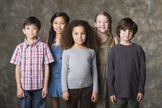Children (6-7, 8-9) posing together, studio shot. Photo : Rob Lewine