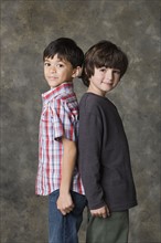 Two boys (6-7, 8-9) posing back to back, studio shot. Photo : Rob Lewine