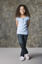 Portrait of smiling girl (8-9) standing, studio shot. Photo: Rob Lewine