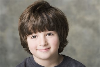 Portrait of smiling (6-7) boy, studio shot. Photo : Rob Lewine
