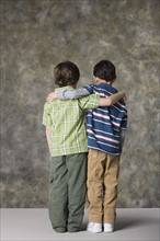 Rear view of two boys (6-7, 8-9) standing together, studio shot. Photo : Rob Lewine