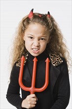 Girl (8-9) posing wearing devil costume, studio shot. Photo : Rob Lewine