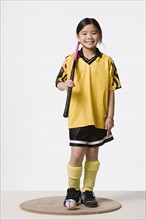 Portrait of smiling girl (8-9) wearing field hockey costume, studio shot. Photo : Rob Lewine