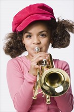 Portrait of girl (8-9) playing trumpet, studio shot. Photo: Rob Lewine