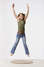 Studio shot of smiling girl (8-9) jumping, studio shot. Photo : Rob Lewine