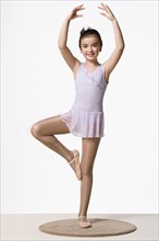 Girl (8-9) in tutu dress practicing ballet dancing, studio shot. Photo : Rob Lewine