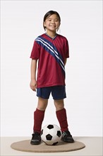 Smiling girl (8-9) wearing soccer uniform, studio shot. Photo : Rob Lewine