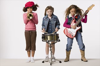 Three girls (8-9) playing instruments together, studio shot. Photo: Rob Lewine