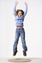 Smiling girl (8-9) jumping, studio shot. Photo : Rob Lewine