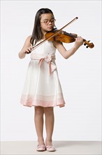 Girl (8-9) playing violin, studio shot. Photo : Rob Lewine