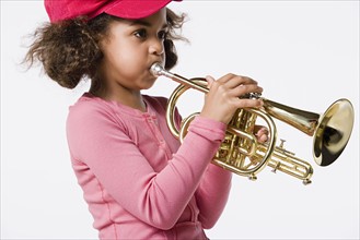 Studio portrait of girl (8-9) playing trumpet. Photo: Rob Lewine