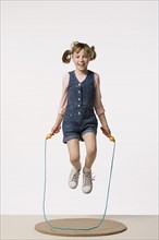 Studio portrait of girl (8-9) jumping on rope. Photo: Rob Lewine