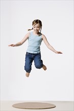 Studio portrait of girl (8-9) jumping. Photo : Rob Lewine