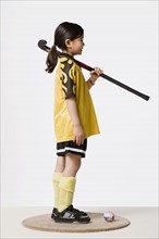 Studio portrait of girl (8-9) wearing sports clothes and holding hockey stick. Photo : Rob Lewine