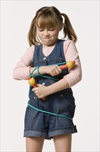 Studio portrait of girl (8-9) wrapped in jump rope. Photo : Rob Lewine