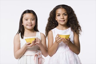 Studio portrait of girls (8-9) holding bowls. Photo: Rob Lewine