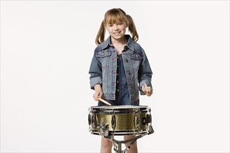 Studio portrait of girl (8-9) playing drums. Photo : Rob Lewine