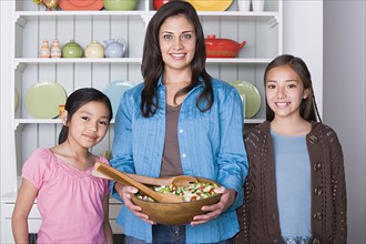 Portrait of mother with two daughters (8-9, 10-11) in kitchen. Photo : Rob Lewine