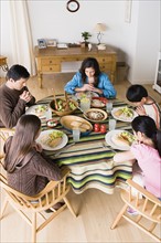 Family with three children (8-9, 10-11) praying at table before dining. Photo: Rob Lewine