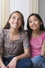 Sisters (8-9, 10-11) listening together to music on headphones. Photo : Rob Lewine