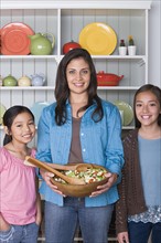 Portrait of mother with two daughters (8-9, 10-11) in kitchen. Photo : Rob Lewine
