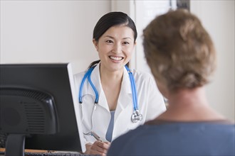 Smiling female doctor talking to patient in her office. Photo: Rob Lewine