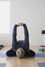 Mature man practicing yoga on mat. Photo: Rob Lewine
