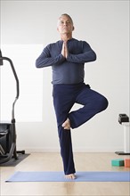 Mature man practicing yoga on mat. Photo : Rob Lewine