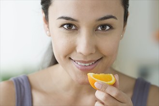 Portrait of attractive woman holding slice of orange. Photo : Rob Lewine
