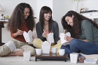 Three female friends eating take out food at home. Photo : Rob Lewine