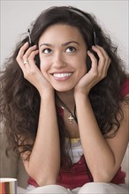 Young woman listening to music and smiling. Photo : Rob Lewine