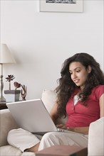 Young woman using laptop at home. Photo : Rob Lewine