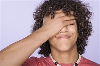 Portrait of teenage boy (14-15) covering eyes with hand. Photo : Rob Lewine