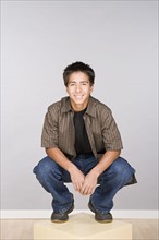 Portrait of teenage boy (16-17) crouching. Photo : Rob Lewine