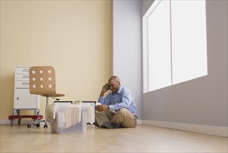 Portrait of businessman sitting on floor in empty office. Photo: Rob Lewine