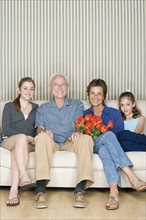 Portrait of grandparents with two granddaughters (8-9, 14-15) sitting together on sofa. Photo: Rob