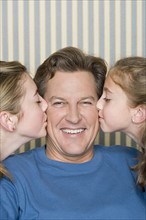 Portrait of father being kissed by two girls (8-9, 14-15) . Photo : Rob Lewine