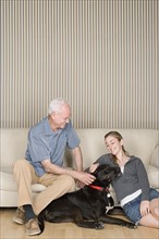 Grandfather with granddaughter (14-15) stroking dog . Photo : Rob Lewine