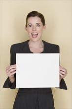 Portrait of happy mid adult woman holding blank sheet of paper. Photo : Rob Lewine