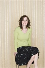 Portrait of happy mid adult woman sitting on chair. Photo : Rob Lewine