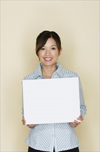 Portrait of happy asian woman holding blank sheet of paper. Photo : Rob Lewine